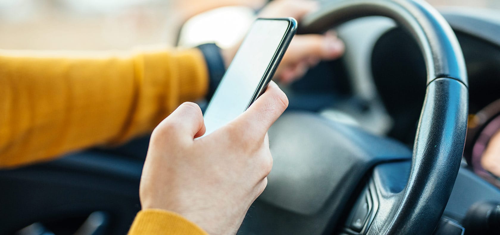 Driver looking at the cell phone while driving.