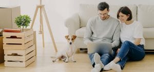 Hiring the Right Roofing Contractor_Blog-Feature Couple with a pet in a rented apartment with furniture and moving boxes.